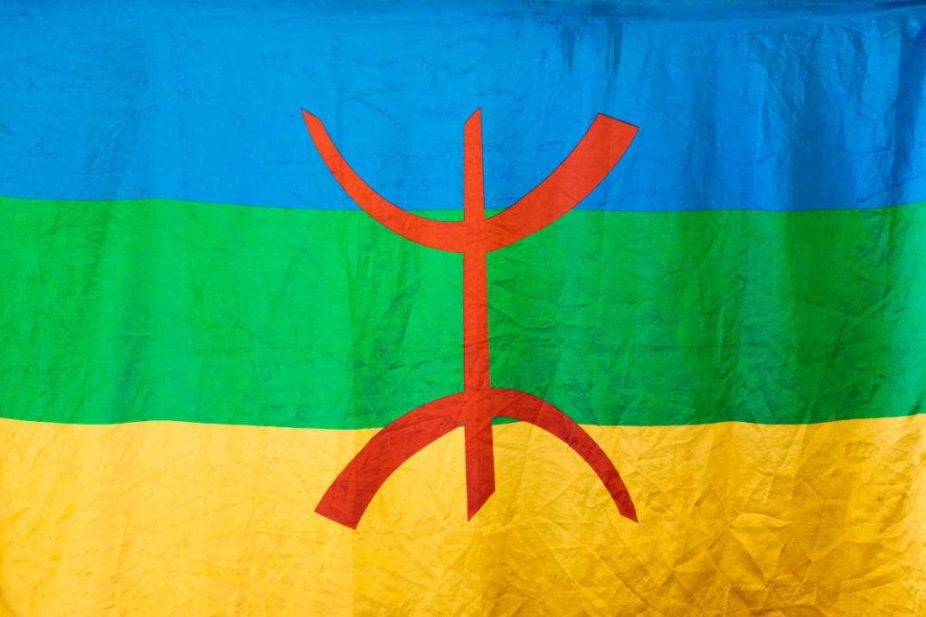 Die blaue grüne und gelbe Amazigh Berber Flagge mit dem roten Yaz Symbol in der Mitte