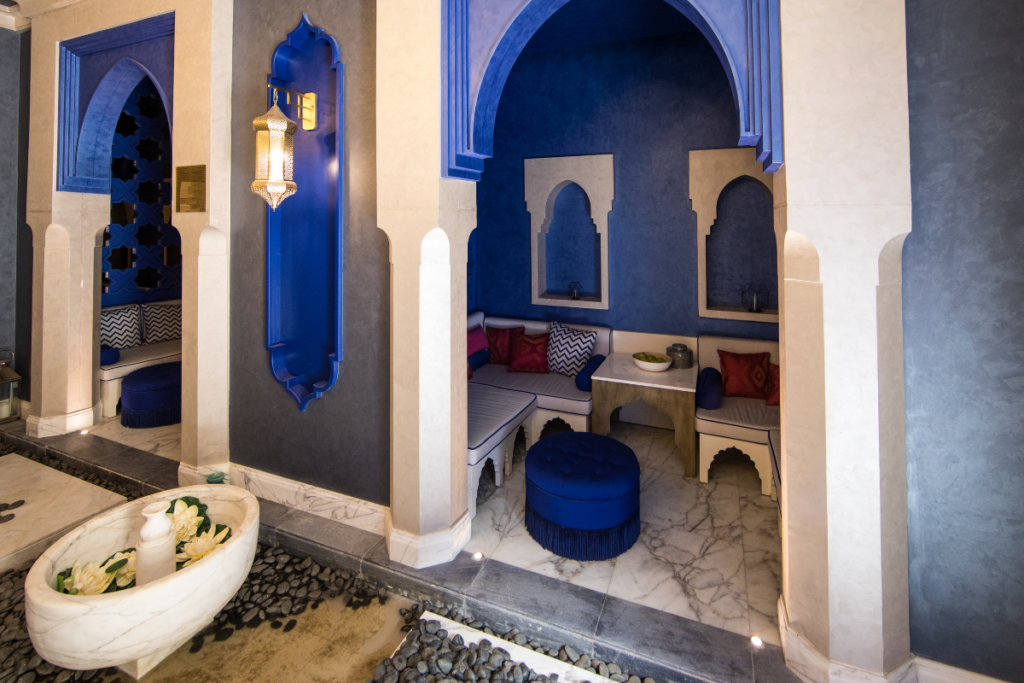 Elegante Spa-Lounge im marokkanischen Stil mit königsblauen Wandnischen, Hocker und orientalischen Laternen